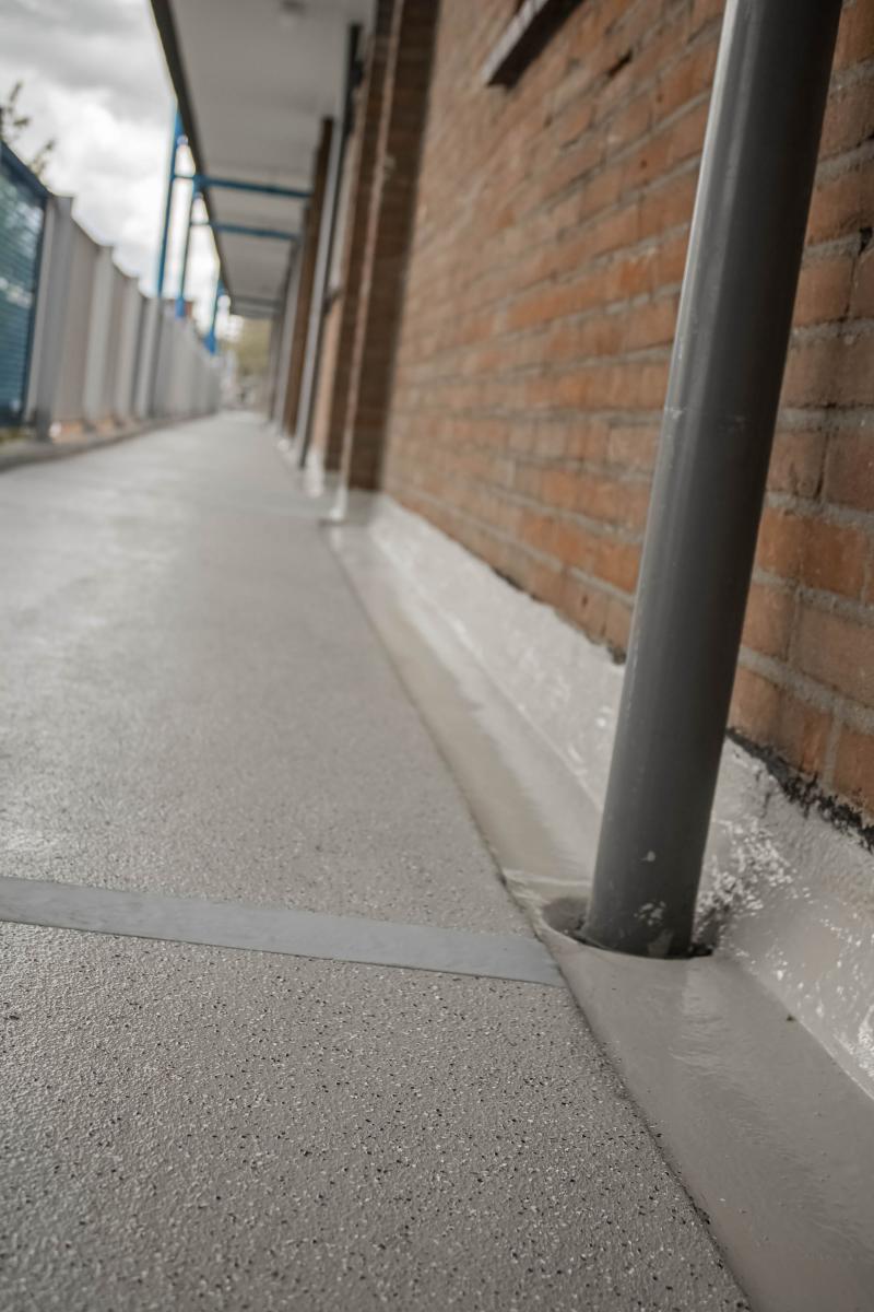 Afgewerkte galerij met naadloze vloer langs gevel
